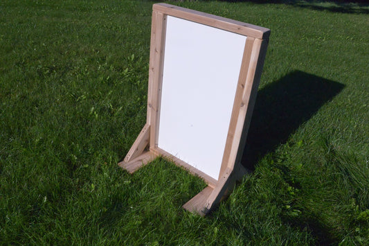 Double-sided outdoor art easel with whiteboard surface on grass
