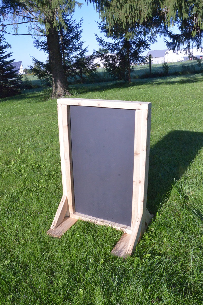 Double-sided outdoor art easel with chalkboard surface on grass
