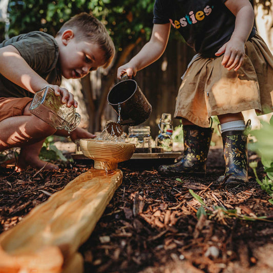 Children playing with a wooden water channeling set outdoors