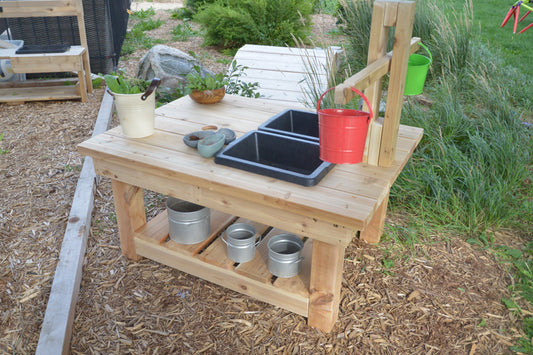 Outdoor cedar Explorer Table with built-in wooden weighing scale, black sink, red bucket, and lower storage shelf.